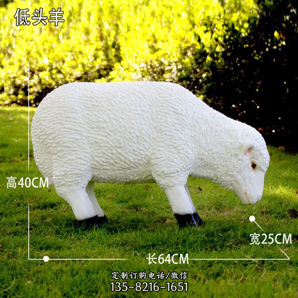 草地上一只低頭吃草的玻璃鋼仿真綿羊雕塑